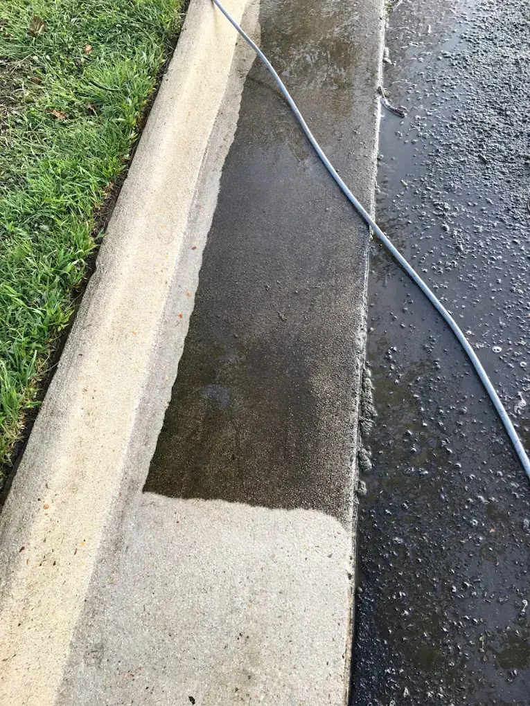 Concrete curb partly pressure washed, clean bright concrete beside dark dirty concrete