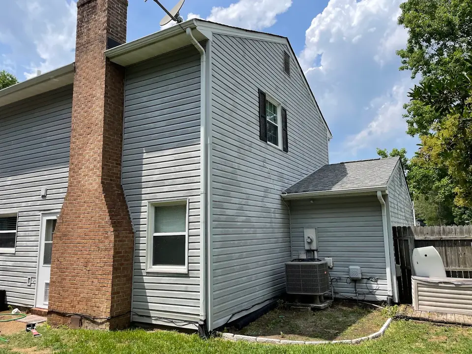 Vinyl siding during a soft wash with algae streaks being lifted off